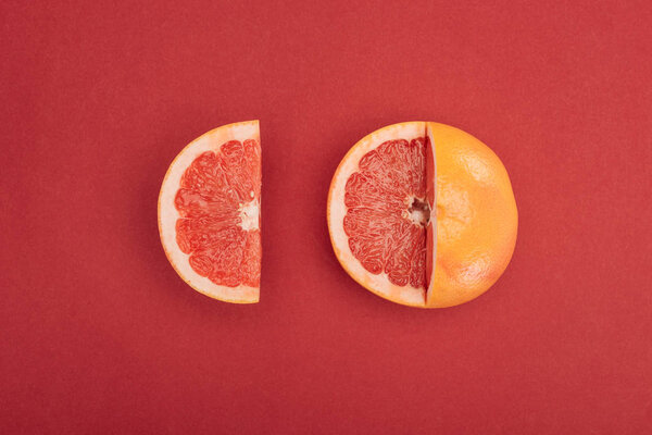 вид сверху на ломтик грейпфрута и частично вырезанный грейпфрут на красном фоне
