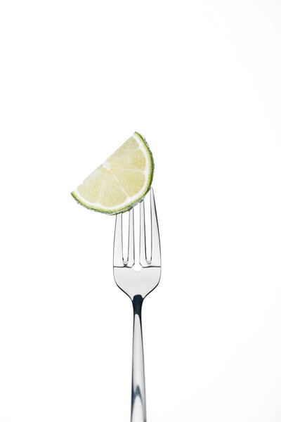 half slice of fresh ripe juicy lime on fork isolated on white