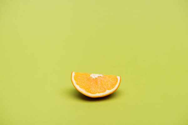 Slice of fresh ripe juicy orange on green background
