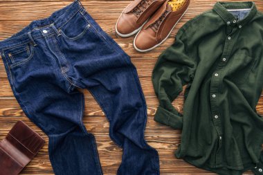 Ahşap arka plan üzerinde kot pantolon, kahverengi ayakkabı ve Yeşil tişörtlü üstten görünüm