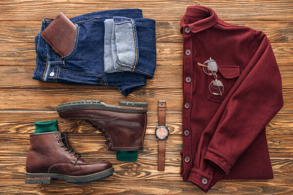 Flat lay with shirt, jeans and leather accessories on wooden background