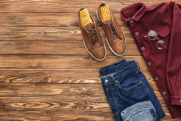 Flat lay with boots, shirt and jeans on wooden background