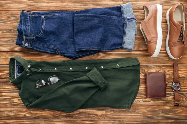 Bovenaanzicht Van Jeans Groene Shirt Lederen Accessoires Houten Achtergrond — Stockfoto