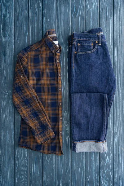 Draufsicht Auf Jeans Und Stylisches Kariertes Hemd Auf Holzgrund — Stockfoto