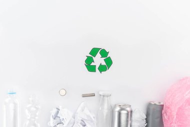 Kutular, plastik ve cam şişeler, piller, kağıt, geri dönüşüm işareti ve pembe plastik torba üstten görünüm