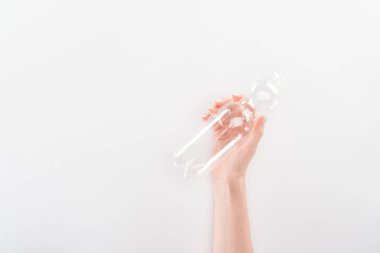 Kısmi görünümü gri arka plan üzerinde boş plastik şişe tutan kadın