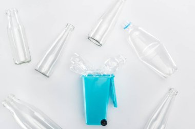 Mavi oyuncak çöp tenekesi ve boş plastik ve cam şişeler üstten görünüm