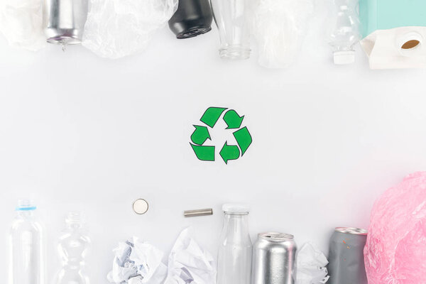 Top view of cans, plastic and glass bottles, batteries, paper, recycling sign, carton bottle and pink plastic bag