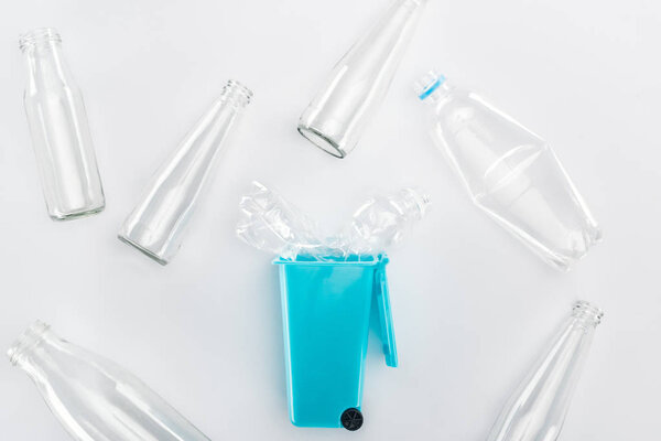Top view of blue toy trashcan and empty plastic and glass bottles