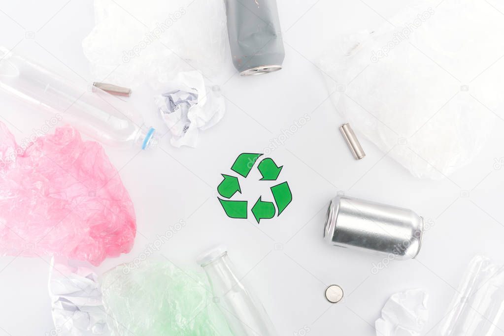 Top view of cans, plastic bags, paper, recycling sign, plastic and glass bottles 