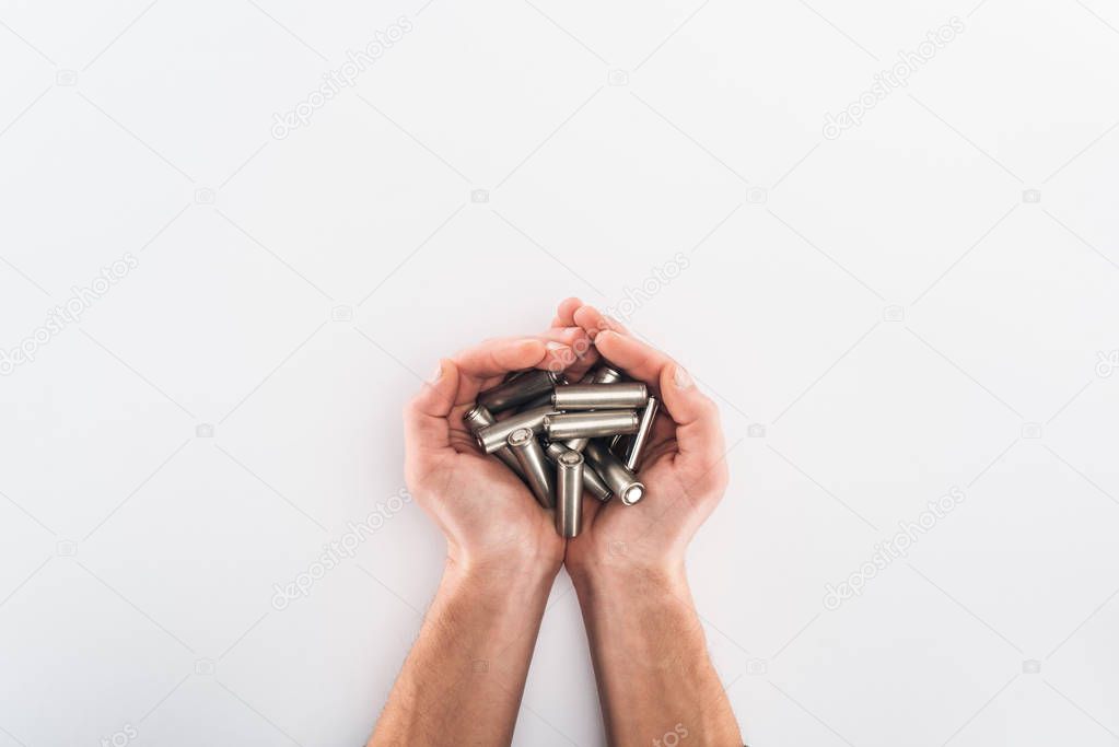 Cropped view of man holding batteries on grey background
