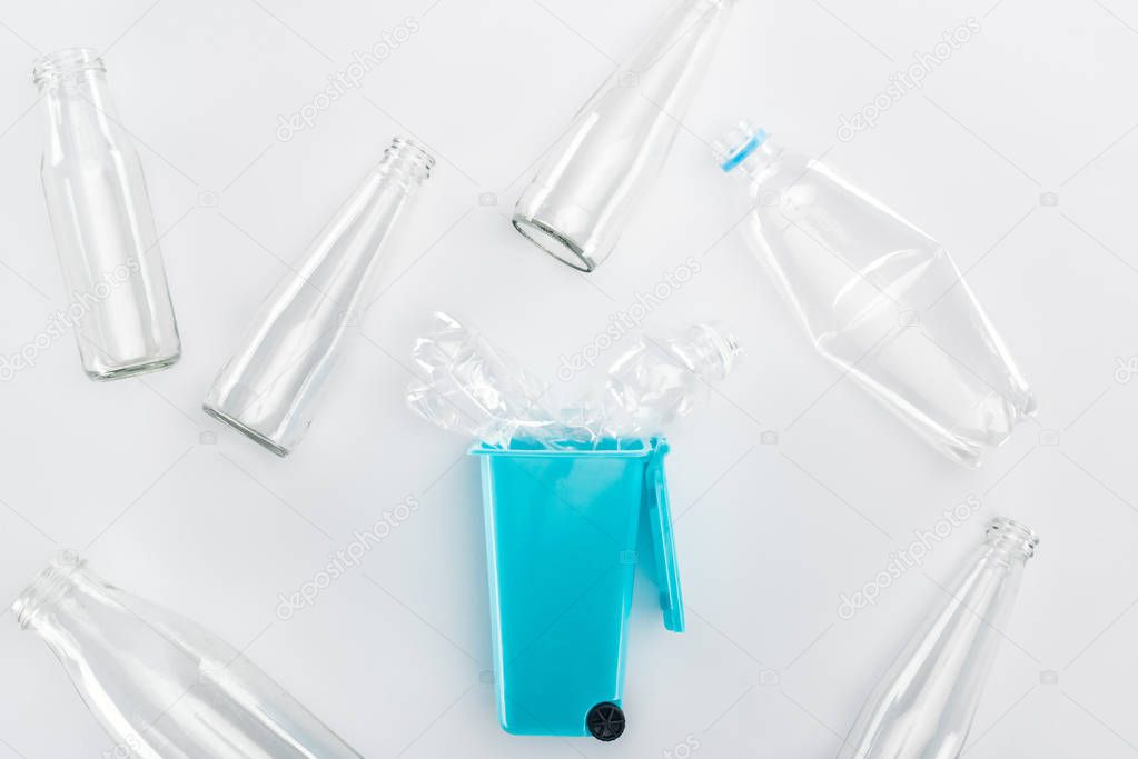 Top view of blue toy trashcan and empty plastic and glass bottles