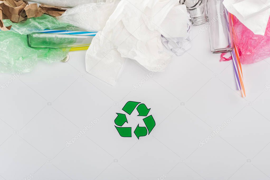 Top view of glass bottles, plastic bags, paper and plastic tubes with recycling sign 