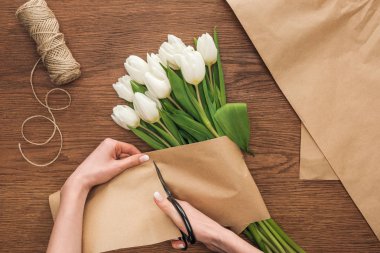 Çiçekçi kesme Kraft kağıt üzerinde ahşap arka plan bahar buket yaparken üzerinde kısmi görünümünü