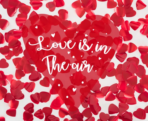 在灰色背景上的美丽的红色心形花瓣的顶部视图与 爱是在空气中 的字母 情人节的概念 — 图库照片