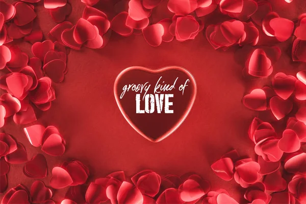 赤の背景 バレンタインデーのコンセプトに 愛のグルーヴィーな種類 の文字と装飾的な花びらを持つ美しい心のトップ ビュー — ストック写真