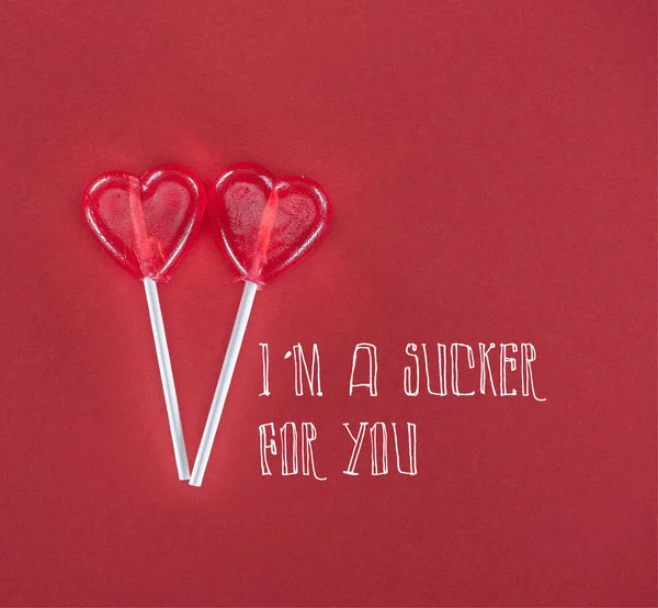两个心形棒棒糖在红色背景与 我是一个吸盘为你 的字母 情人节的概念 — 图库照片