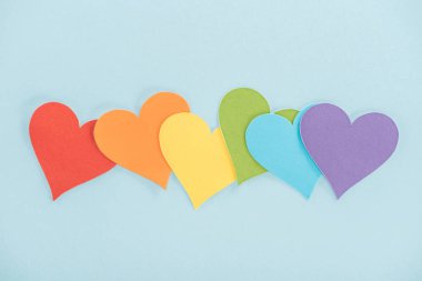 rainbow colored paper hearts on blue background, lgbt concept clipart