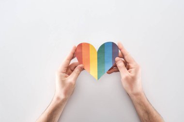 Kağıt kalp gri arka plan, lgbt kavramı üzerinde kısmi gökkuşağı tutan adam görünümünü renkli