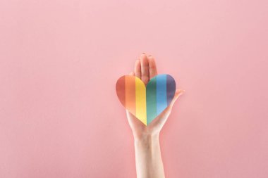 Gökkuşağı renkli kağıt kalp pembe arka plan, lgbt kavramı üzerinde tutan kadın görünümünü kırpılmış
