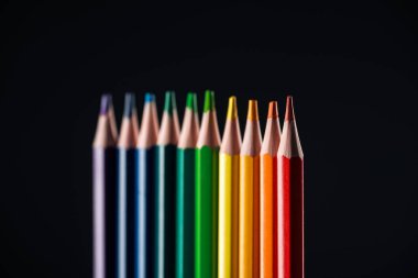 selective focus of rainbow colored pencils isolated on black, lgbt concept clipart