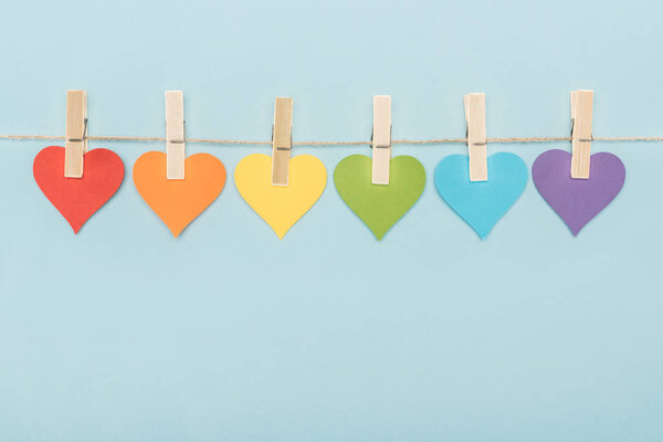 rainbow multicolored paper hearts on rope isolated on blue, lgbt concept