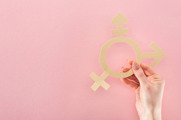 partial view of female hand with paper cut gender sign on pink background, lgbt concept