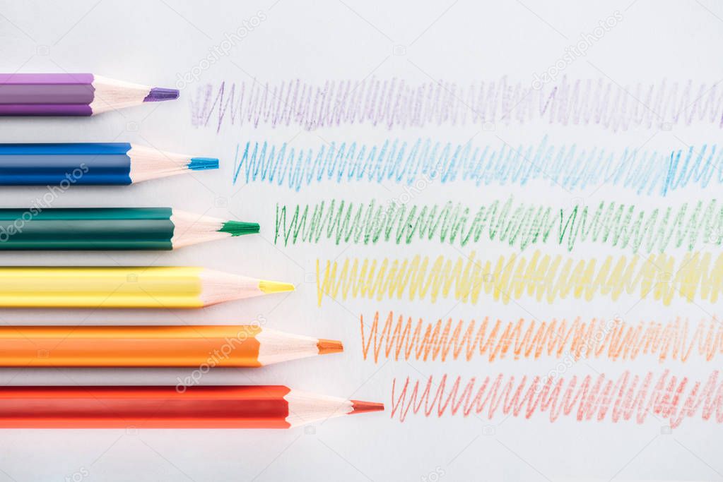 top view of rainbow multicolored pencils and colorful strokes on grey background, lgbt concept