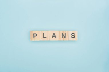 top view of plans lettering made of wooden blocks on blue background clipart