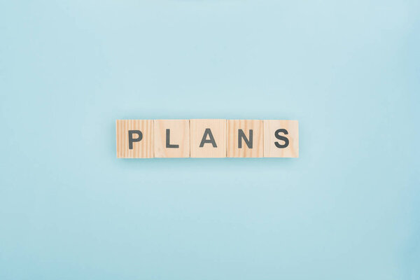 top view of plans lettering made of wooden blocks on blue background