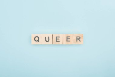 top view of queer lettering made of wooden cubes on blue background clipart
