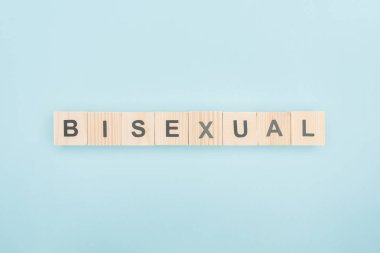 top view of bisexual lettering made of wooden cubes on blue background clipart