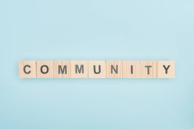 top view of community lettering made of wooden cubes on blue background  clipart