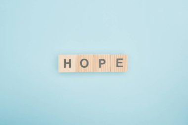 top view of hope lettering made of wooden cubes on blue background  clipart