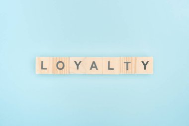 top view of loyalty lettering made of wooden cubes on blue background 