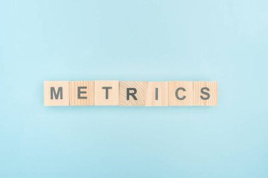 top view of metrics lettering made of wooden cubes on blue background clipart