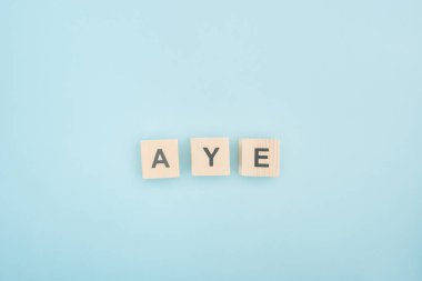 top view of aye lettering made of wooden cubes on blue background clipart