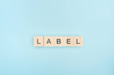top view of lable lettering made of wooden cubes on blue background clipart