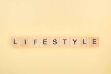top view of lifestyle lettering made of wooden cubes on yellow background clipart