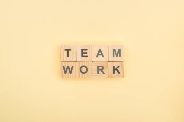 top view of team work lettering made of wooden blocks on yellow background clipart