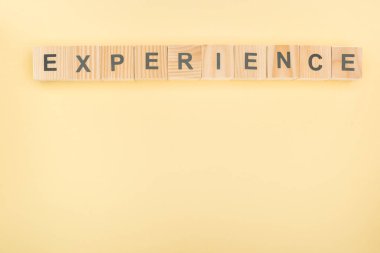 top view of experience lettering made of wooden blocks on yellow background clipart