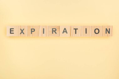 top view of expiration lettering made of wooden blocks on yellow background clipart