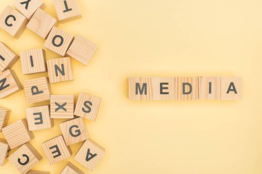 Medya yazı tahta küpleri ile üst görünümden sarı zemin üzerine