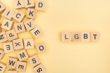 top view of lgbt lettering with wooden cubes on yellow background clipart