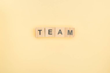 top view of team lettering made of wooden cubes on yellow background clipart