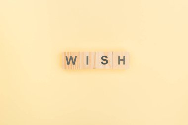 top view of wish lettering made of wooden blocks on yellow background clipart