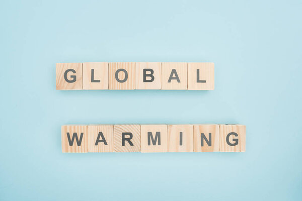 top view of global warming lettering made of wooden cubes on blue background 