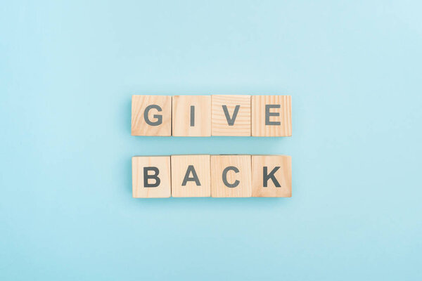 top view of give back lettering made of wooden cubes on blue background