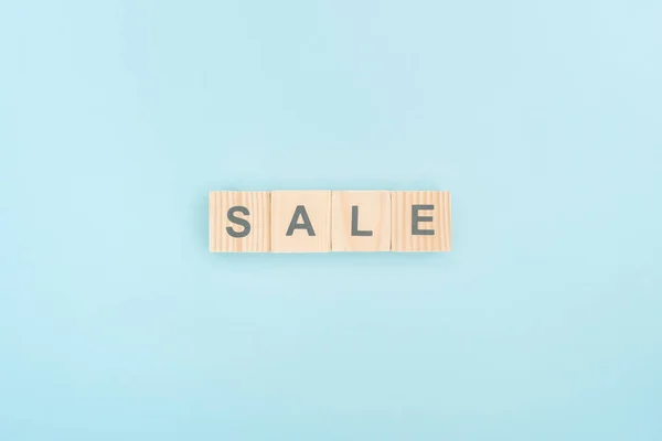 top view of sale lettering made of wooden cubes on blue background