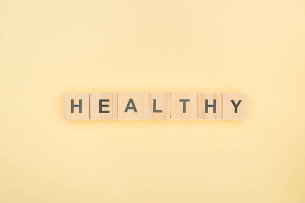 top view of healthy lettering made of wooden cubes on yellow background